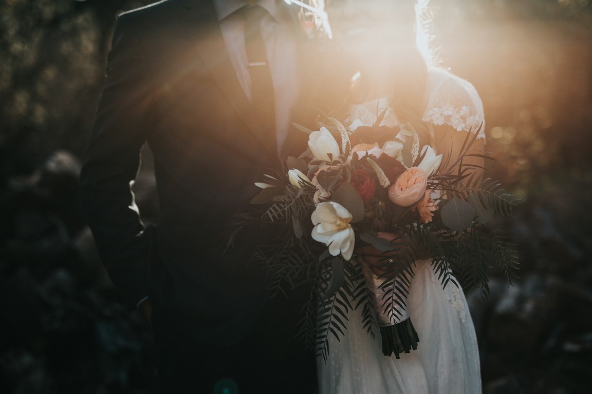 bride standing beside the groom while holding a boquet wedding rings